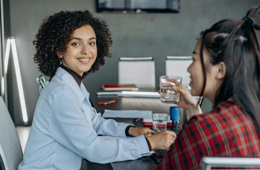 Two women engaged in a professional discussion in a modern office setting.